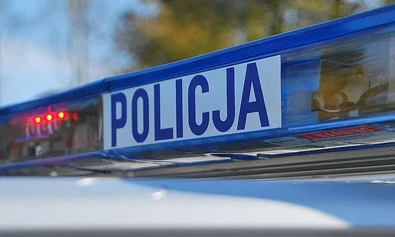 Fragment niebieskiego świetlnego dachu policyjnego radiowozu z napisem POLICJA.