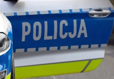 Fragment policyjnego radiowozu z napisem POLICJA na drzwiach.